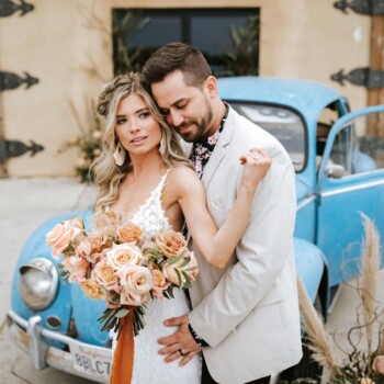 Photo Credit: Tony G Photo
tonigphoto.com @TonyGPhoto (Instagram) Shows a bride and groom with boho chic style posing in front of a baby blue Volkswagen Beetle.