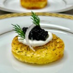 Close-up of a plated caviar appetizer with crème fraîche and dill garnish