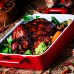 Shows a red baking pan filled with roasted chicken and vegetables.