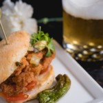Fried chicken sandwich with microgreens, tomatoes, and roasted chili pepper