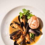 Plated mussels with fresh garnish and bread roll from The Painted Table catering