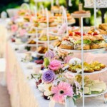 Buffet-style high tea sandwich display with colorful floral arrangements