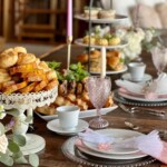 Elegant high tea place setting with vintage goblet, scones, and bread selections