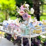 Sweet table with guest favors and floral centerpiece at a tea party themed baby shower
